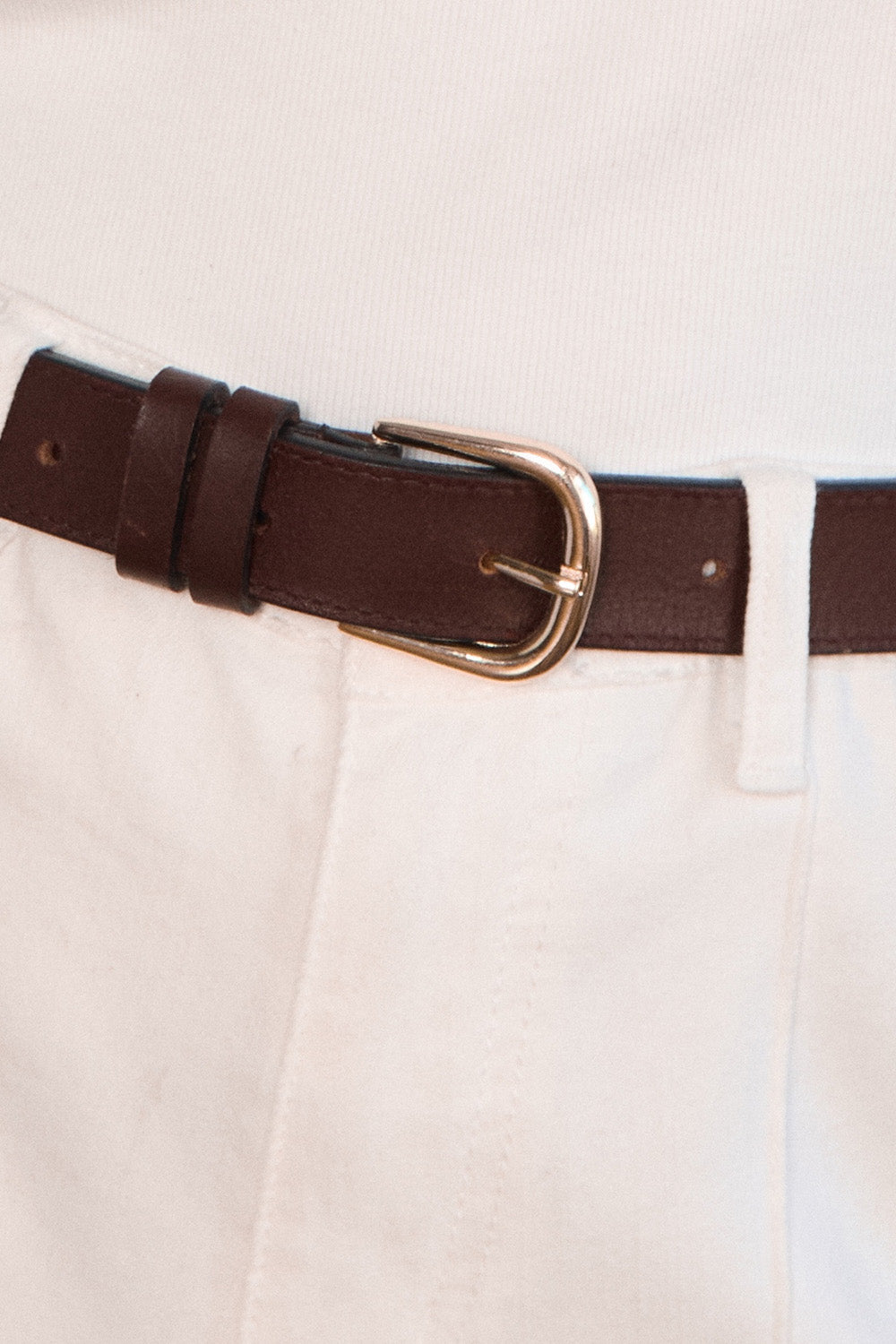 Close-up of a brown belt with a gold buckle on beige pants.