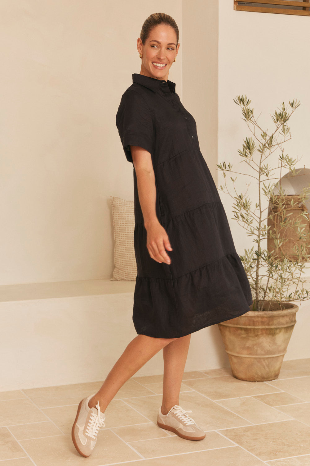 Model wearing the Winslow Linen Knee-Length Dress in Black with breezy tiered shape, Adrift Clothing