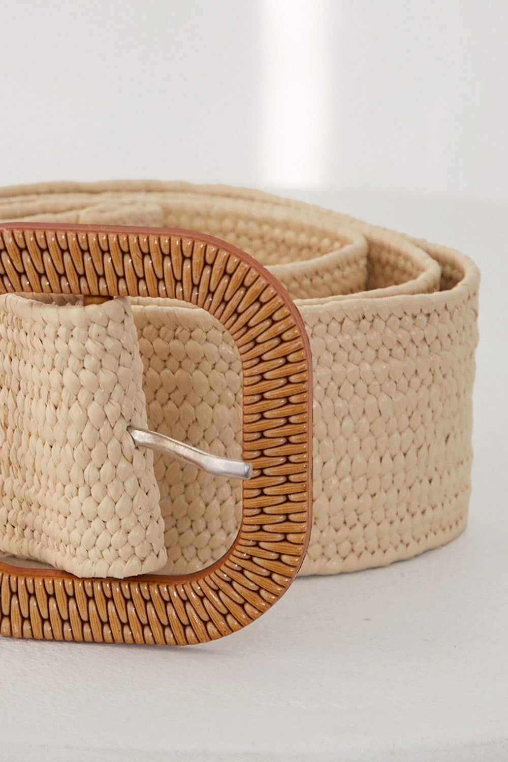 Beige woven belt with a square buckle on a light background