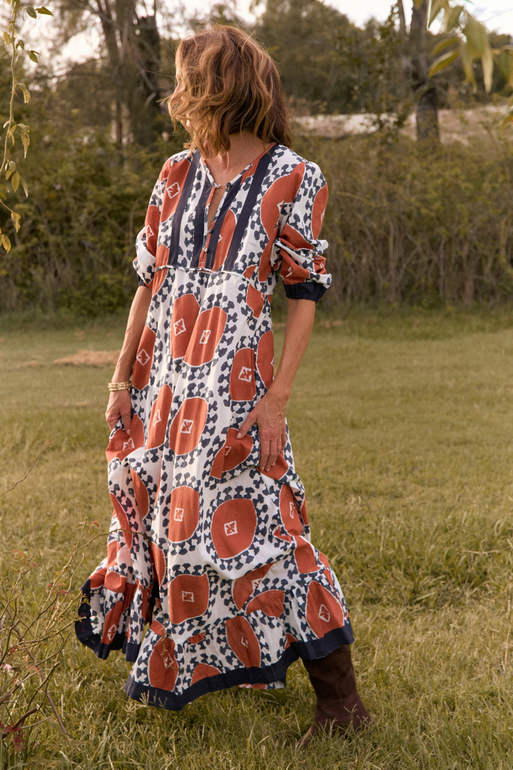 Woman in a patterned dress standing in a grassy field