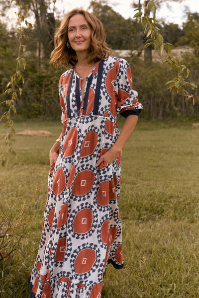 Woman wearing a patterned dress standing in a grassy outdoor setting