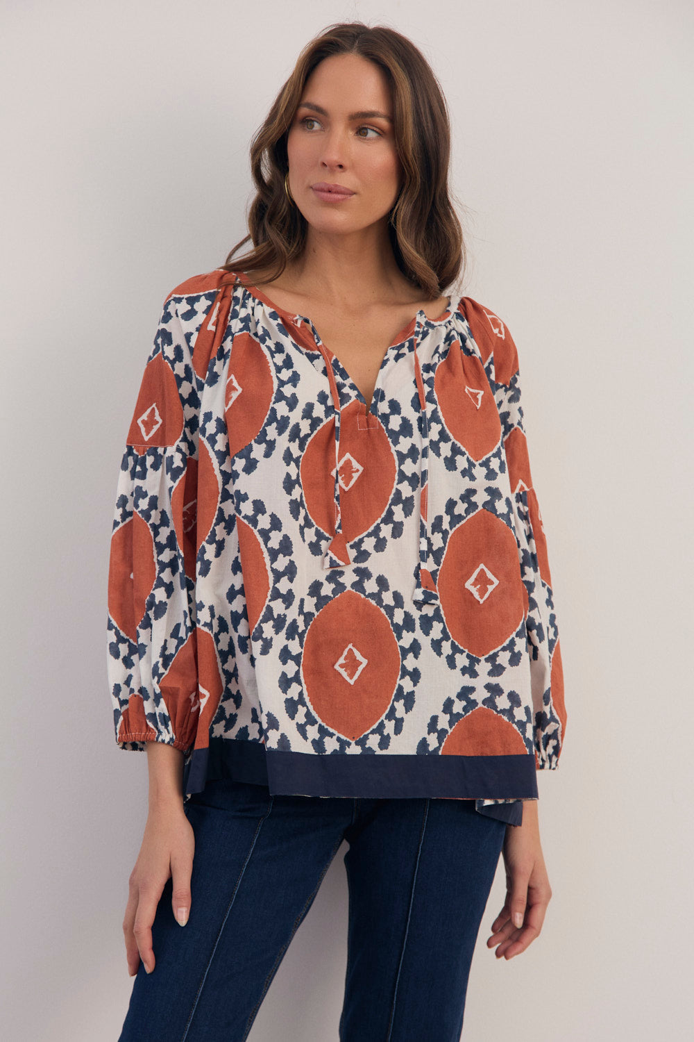 Woman wearing a patterned blouse with a plain background