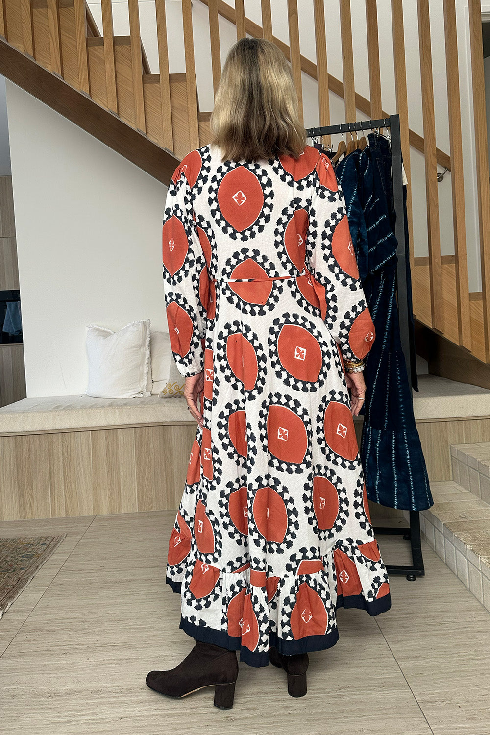 Woman wearing a long dress with red and black pattern in a home setting