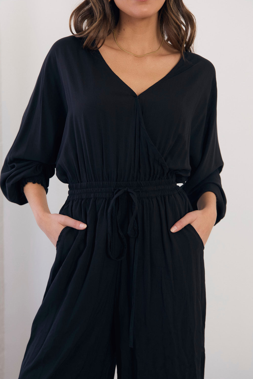 Black jumpsuit worn by a person on a white background